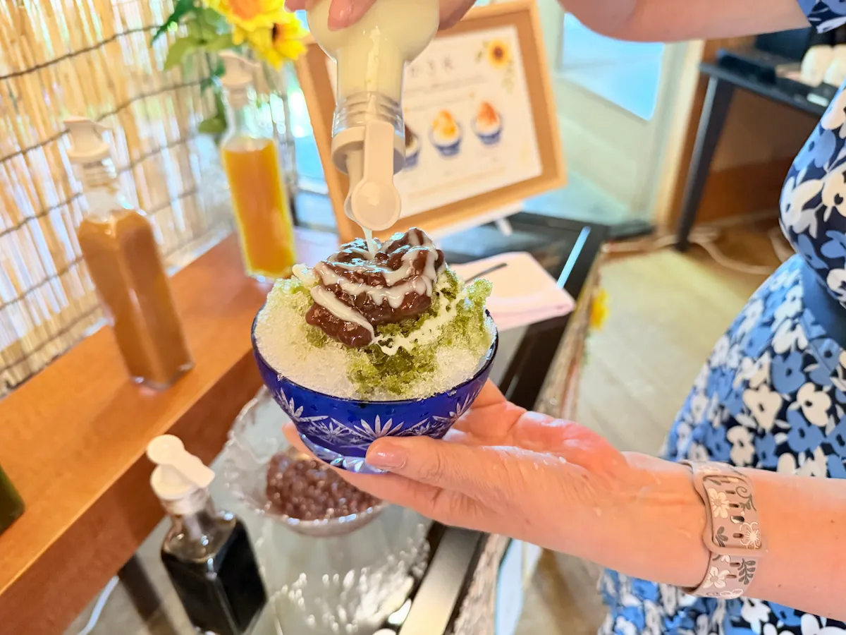 抹茶小豆かき氷に練乳をかける編集長